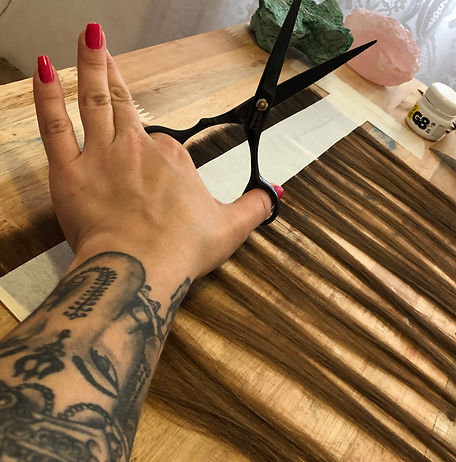 Mãos artesanais cortando e preparando uma trança de cabelo humano para confecção da microfita